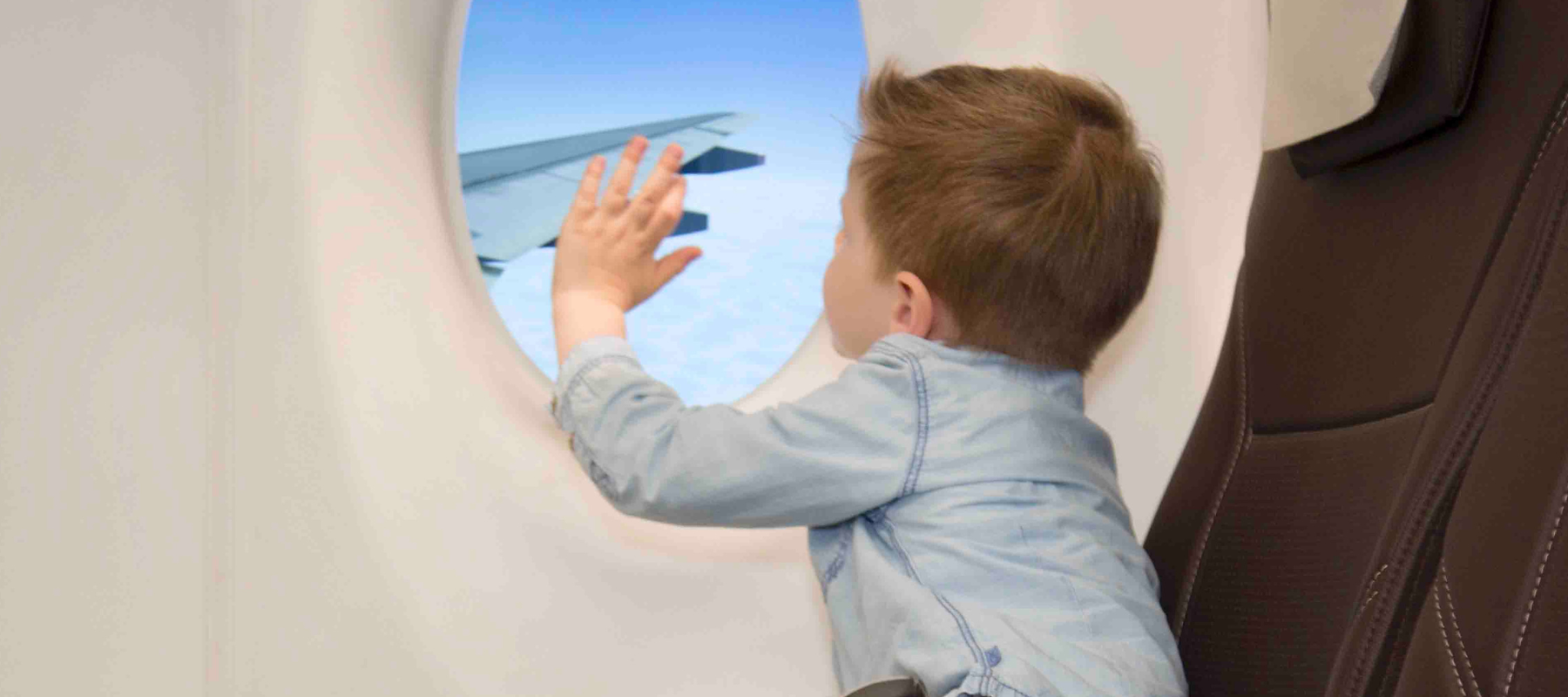 child waving out plane window