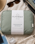 Green packing cube with 'Flyaway' label on a travel-themed surface with accessories.