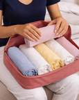 Person organizing folded clothes into a rust color travel packing cube.