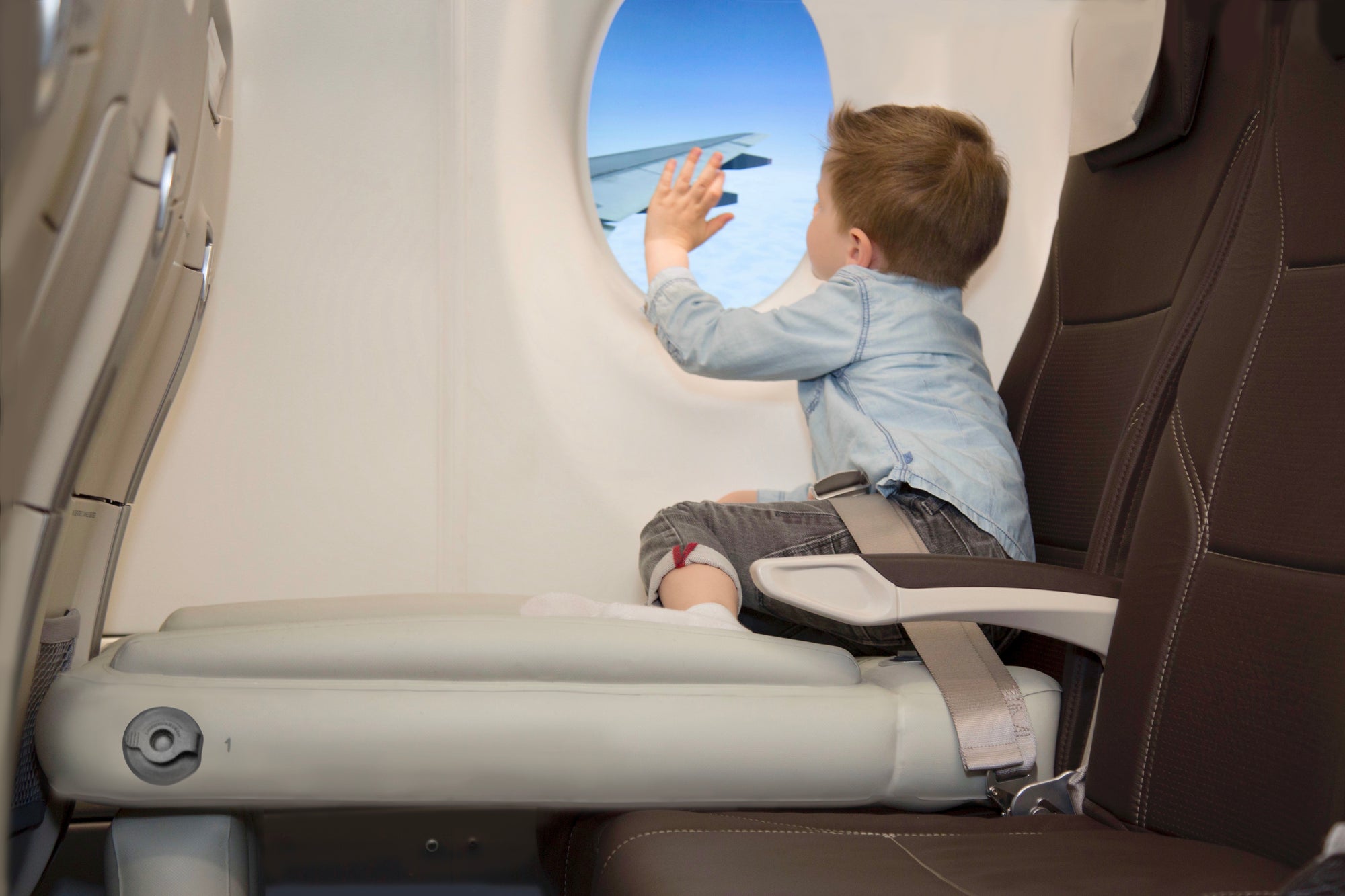 Boy looking out of a plane window and waving