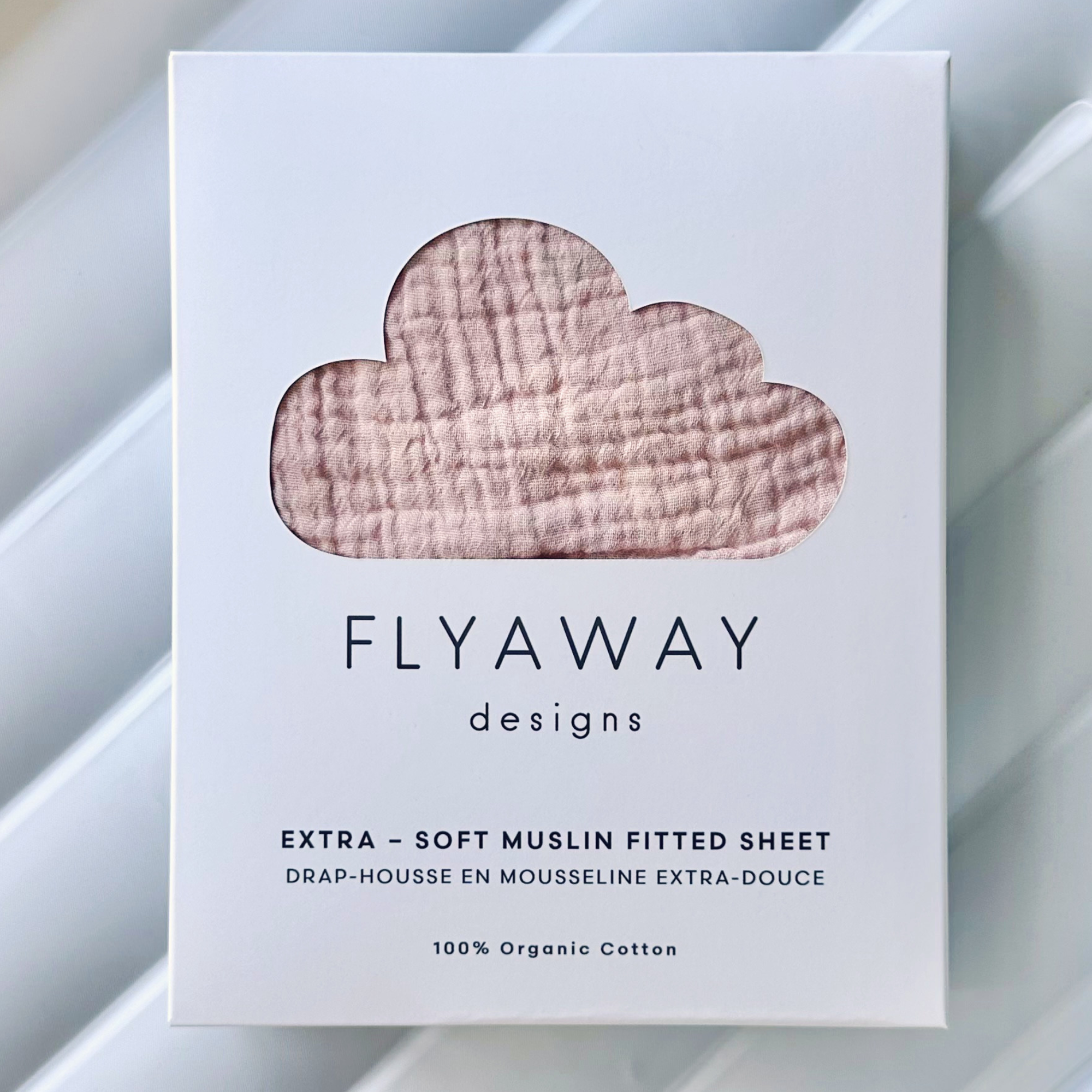 Box of Flyaway Designs extra-soft muslin fitted sheet on a light background